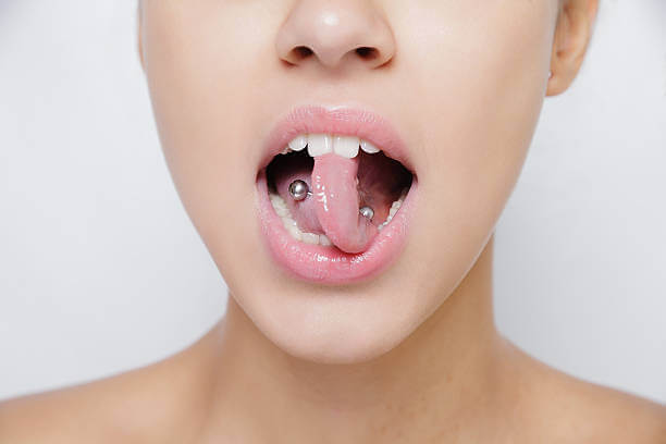 Beautiful woman sticking out her tongue and showing her young piercing